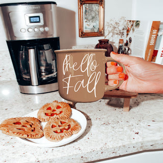hello fall mug next to stack of sweaters
hello fall coffee cup on kitchen island
hello fall mug on round wooden riser
hello fall mug with neutral fall tablescape