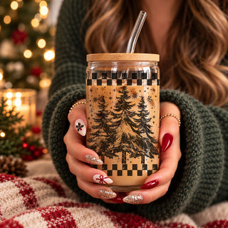 Shop this retro Christmas tree 17oz glass tumbler featuring evergreen trees, snowflakes, and a checkered border. Includes bamboo lid and reusable straw. A cute holiday iced coffee cup and Christmas gift for coffee lovers, moms, teachers, coworkers, and friends.