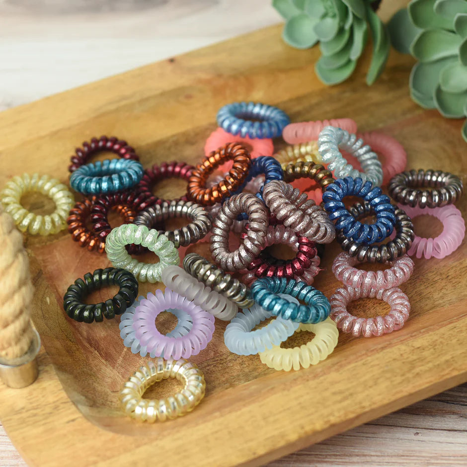a wooden tray topped with lots of different colored hair ties